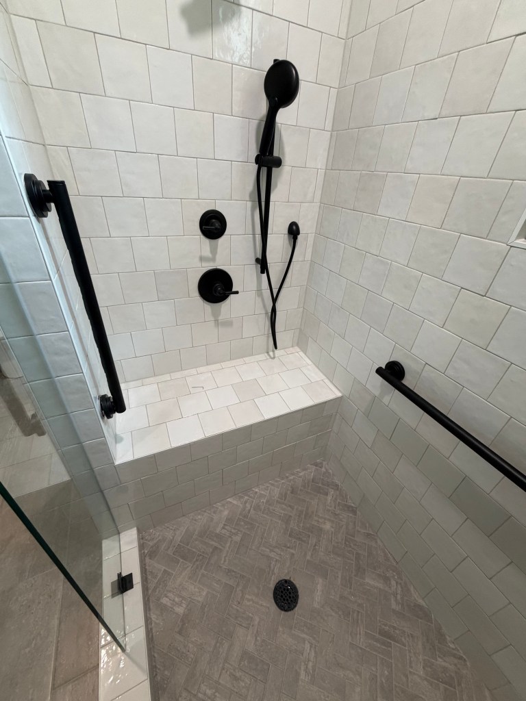 Matte black Moen grab bars professionally installed to provide dependable bathroom support while complementing the room’s modern fixtures and finishes.